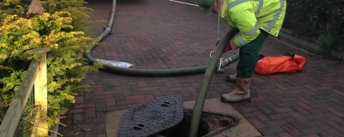 Septic tank cleaning technician servicing a septic tank with a vacuum hose in Jacksonville, FL